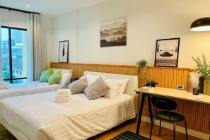 A hotel room with two beds, a desk, a chair, and a window with curtains.