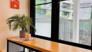 A room with a large window, a wooden table with a potted plant, and a red artwork on the wall. - Stylish Modern Home 4Bedroom 7Bed 200m BTS PhraKhanong, 10min ThongLo (Bangkok)