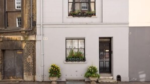 Un bâtiment à deux étages, doté d’une façade blanche, d’une porte noire et de fenêtres ornées de jardinières.