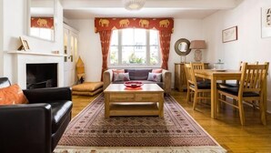 Un salon avec une cheminée, un canapé, une table basse, une table à manger et des chaises.