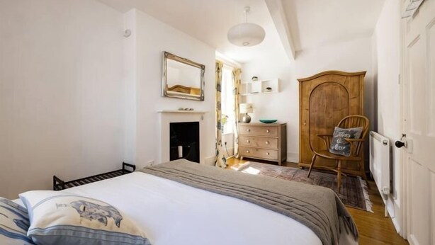 Une chambre à coucher avec un lit, une commode, une chaise et un miroir au mur.