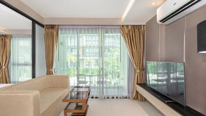 A modern living room with a sofa, a coffee table, and a flat-screen TV. - 1-bedroom Condo Mida Grand Surin Phuket (Choeng Thale)