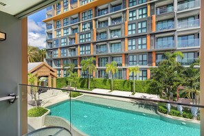 Ein modernes Hotel mit großem Pool, mehreren Balkonen und üppiger Bepflanzung.