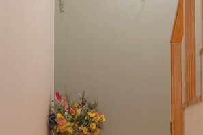 A corner of a room with a wooden door frame and a floral arrangement on the wall.