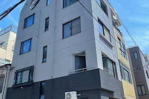 Un immeuble à plusieurs étages, doté d’une façade sobre, de grandes fenêtres et d’un appareil de climatisation visible.