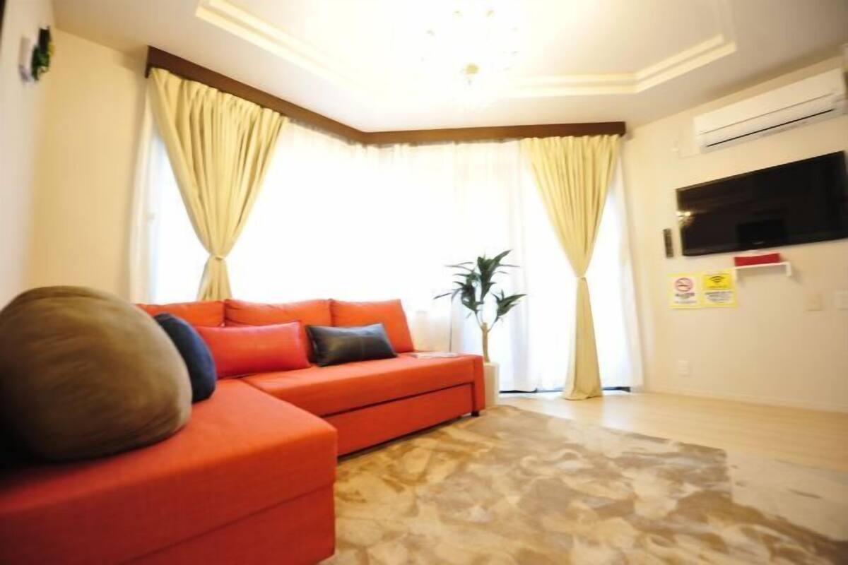 A living room with a sofa, a plant, and a flat-screen TV.