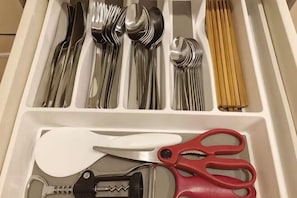 Un tiroir contenant des ustensiles et une paire de ciseaux à manches rouges.