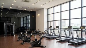 Een sportschool met loopbanden, hometrainers en een krachttrainingapparaat.