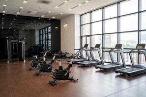 Un gimnasio con cintas de correr, bicicletas estáticas y una máquina de pesas.