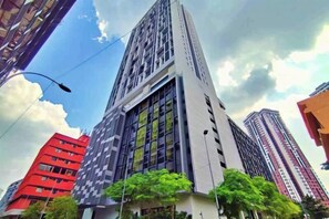 Un edificio alto con varios pisos, rodeado de otros edificios.