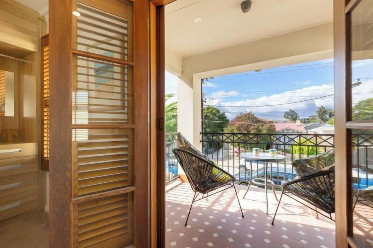 Un balcón con piscina, dos sillas y vistas del barrio.