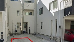 Un estrecho patio urbano con una línea roja que delimita una zona, rodeado de edificios con numerosas ventanas y puertas.
