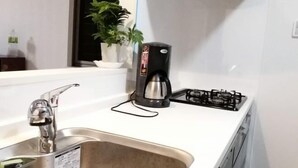 A kitchen with a stainless steel sink, a coffee maker, and a gas stove.