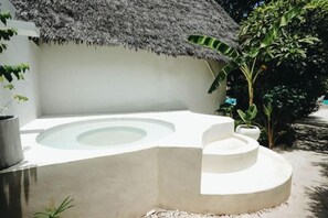 A circular hot tub with a thatched roof, surrounded by a white wall and potted plants. - Seconda Stella Romantic Hideaway (Kusini)