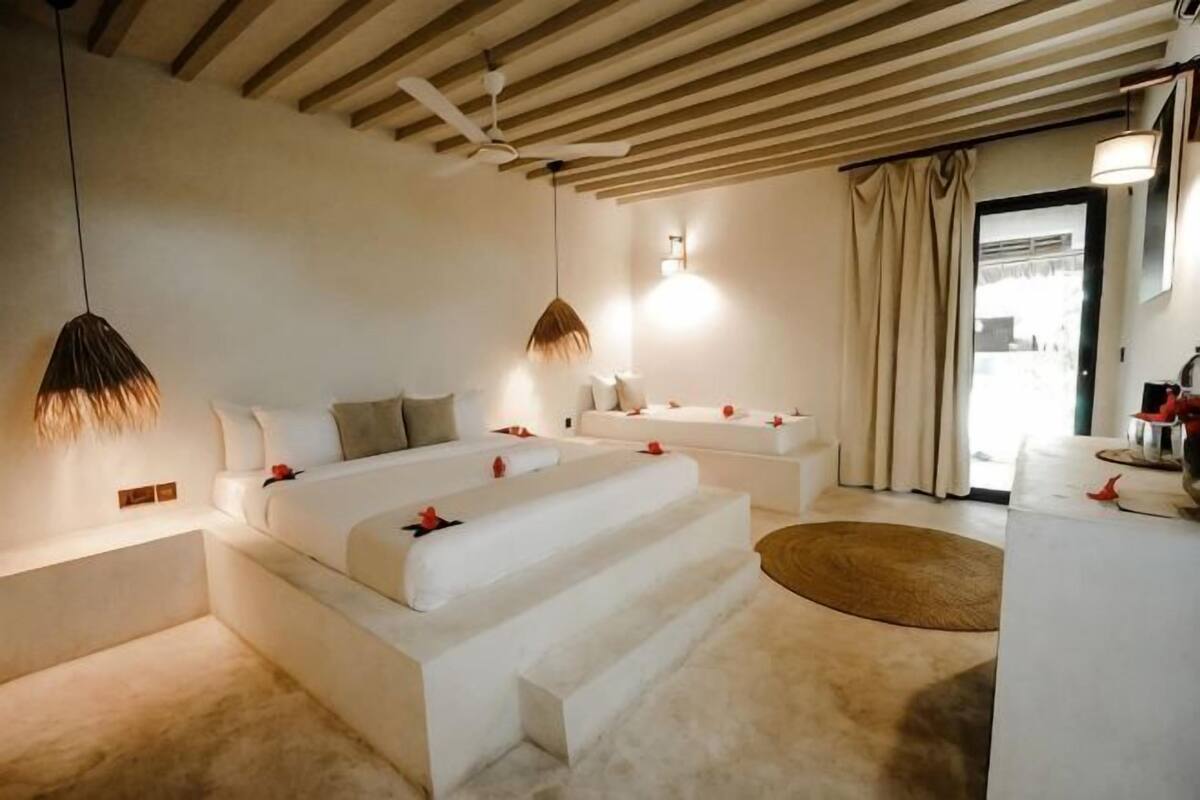 A modern bedroom with a large bed, bedside tables, and a view of the outdoors.