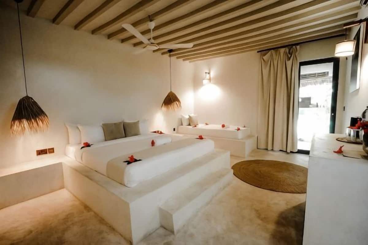 A modern bedroom with a large bed, bedside tables, and a view of the outdoors.