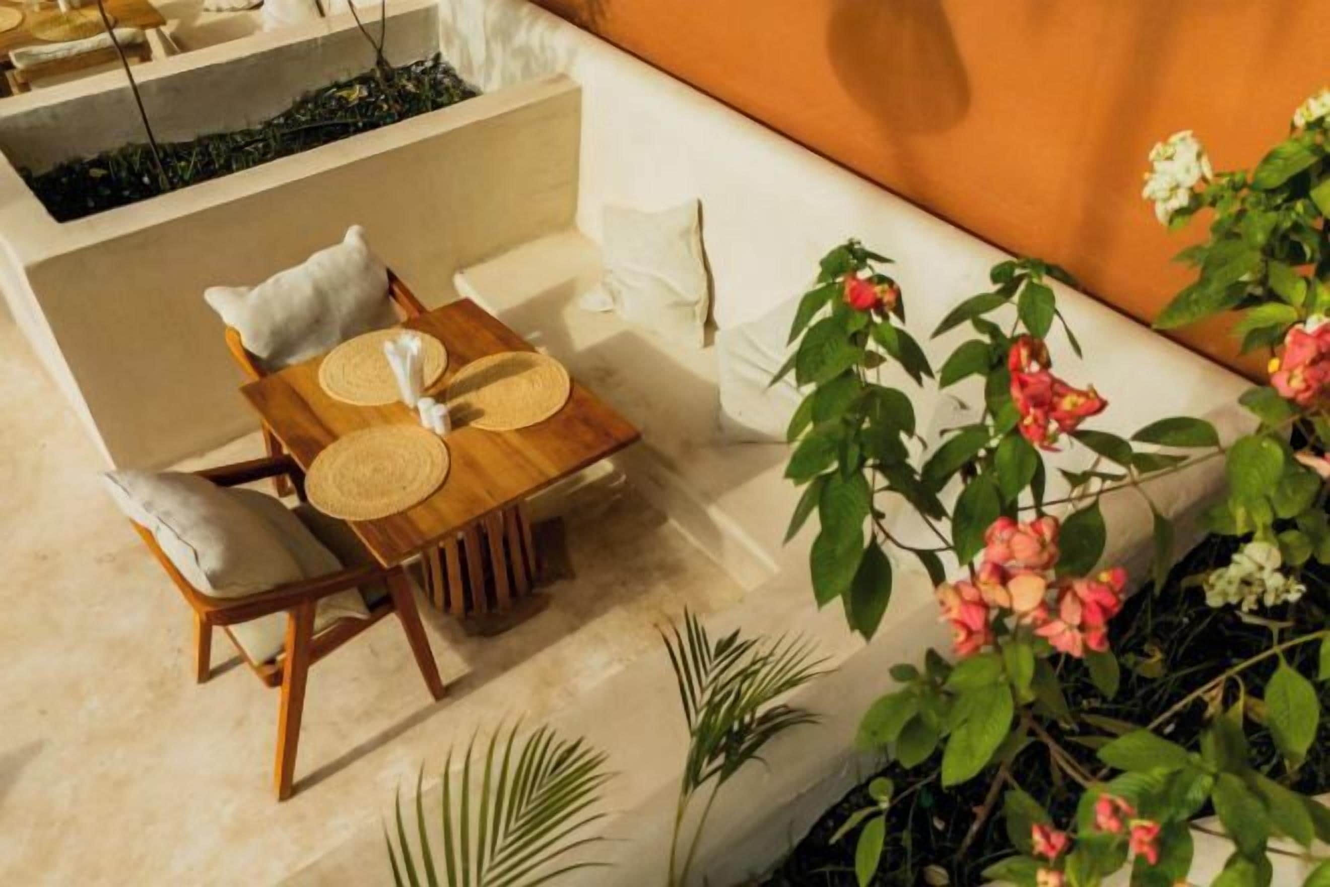 Un'area salotto all'aperto con tavolo e sedie, circondata da piante e fiori.
