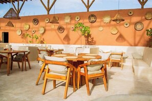 An outdoor patio with wooden tables and chairs, a sofa, and decorative wall art. - Seconda Stella Romantic Hideaway (Kusini)
