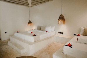 Een hotelkamer met twee bedden, een plafondventilator en hanglampen.