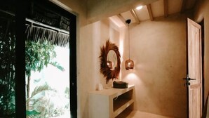A bathroom with a shower, a vanity with a mirror, and a door. - Seconda Stella Romantic Hideaway (Kusini)