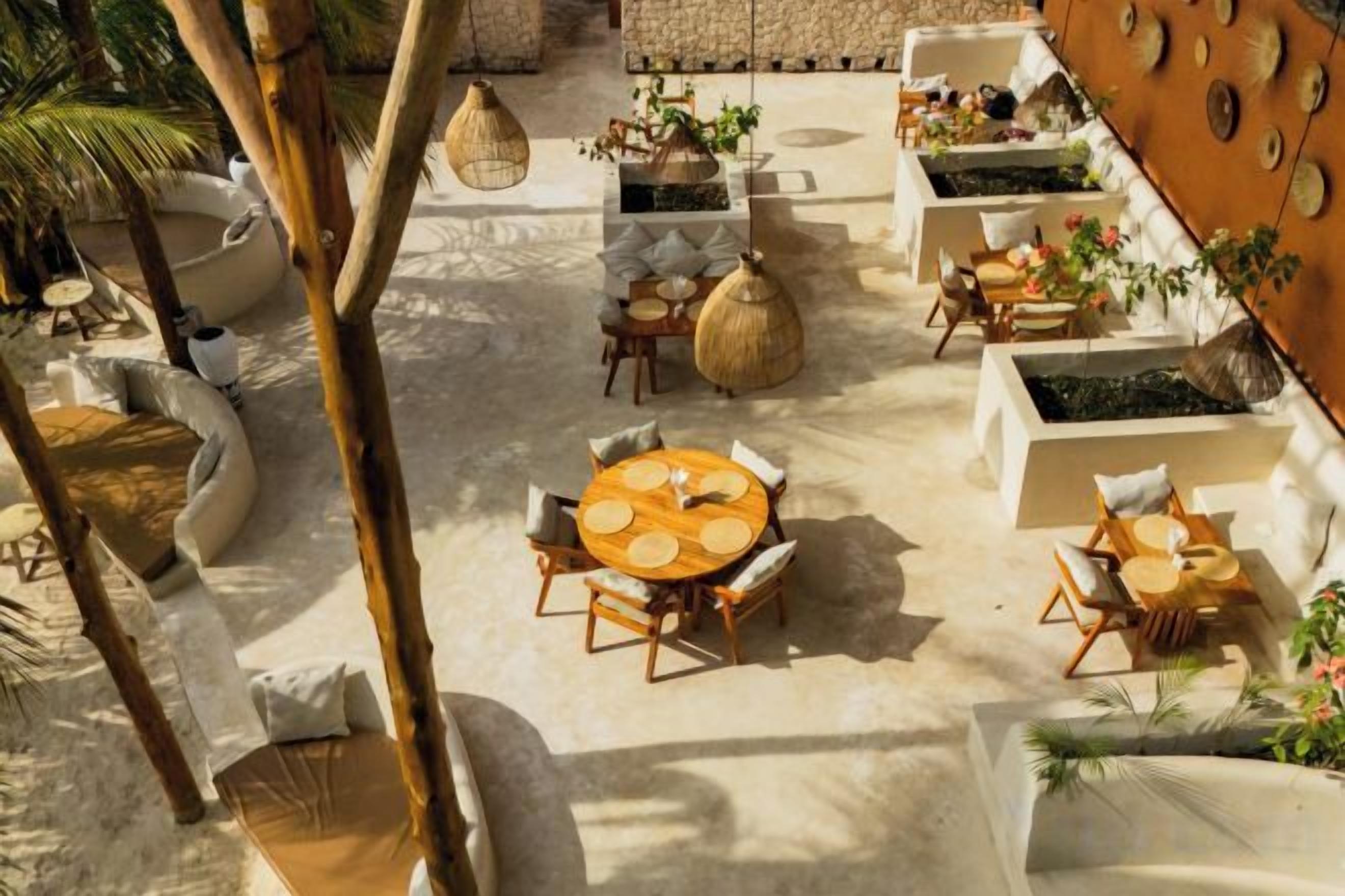 An outdoor patio area with round tables and chairs, planters, and hanging light fixtures.