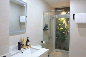 A bathroom with a glass shower enclosure, a white sink with a soap dispenser, and a mirror above the sink. - Central, Near Airport, Dragon Bridge - Gau's House (Da Nang)