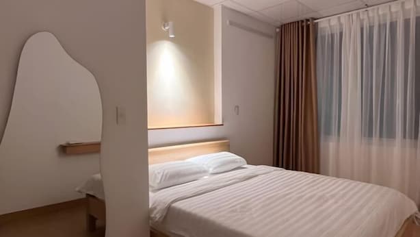 A modern hotel room with a wooden bed, a large mirror, and sheer curtains. - Central, Near Airport, Dragon Bridge - Gau's House (Da Nang)