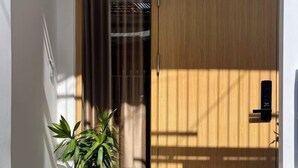 A wooden door with a black handle, a potted plant to the left, and a white wall. - Central, Near Airport, Dragon Bridge - Gau's House (Da Nang)