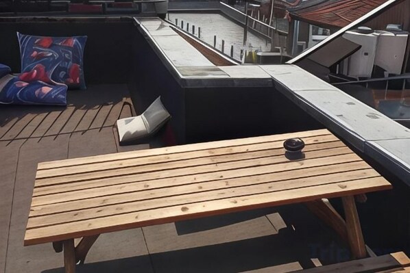 A rooftop terrace with a wooden table and a camera. - Ganbaru Tours - Flats in Galata (Istanbul)