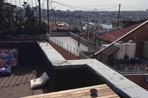 A rooftop terrace with a view of a cityscape, a small pool, and a wooden deck. - Ganbaru Tours - Flats in Galata (Istanbul)