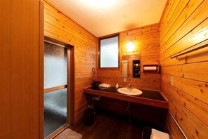 Bany amb panells de fusta, un lavabo, un mirall i una finestra.