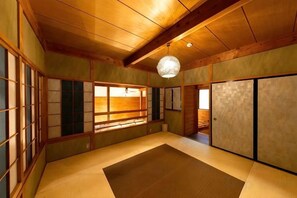 A traditional Japanese room with tatami flooring, sliding doors, and a hanging light fixture. - Cottage morikaze terrace (Nasu)