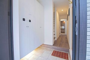 Un couloir avec un sol carrelé, un tapis rouge et une porte dotée d’une poignée.
