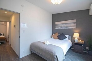 A bedroom with a bed, bedside table, lamp, and a painting on the wall. - Tabitime Shojihigashi - 2min walk to subway station / 4LDK / Max8ppl (Osaka)