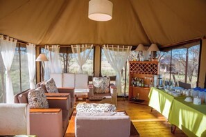 A tented accommodation with a seating area, a bar, and a view of the outdoors. - Kenzan Matawi Serengeti camp (Serengeti)