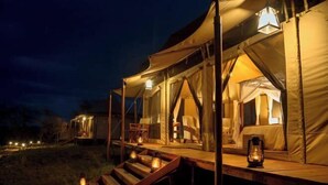 Een tentenverblijf met een houten terras en lantaarns.