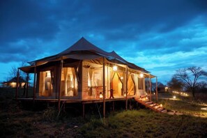 A tent-style accommodation with a covered outdoor area, steps leading to the entrance, and a view of the surrounding landscape. - Kenzan Matawi Serengeti camp (Serengeti)