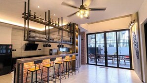 Een moderne keuken met een bar, een plafondventilator en uitzicht door grote schuifdeuren.