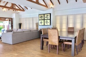 A modern interior with a dining table and chairs, a sofa, and a wall-mounted light panel. - Baan Chao Lay (Koh Samui)
