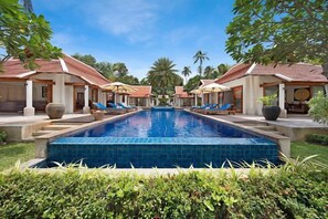 A swimming pool with lounge chairs, a covered seating area, and a tropical garden setting. - Baan Chao Lay (Koh Samui)