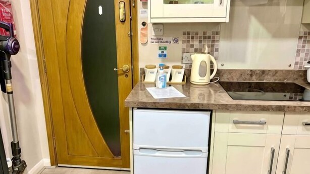 Una cocina compacta con microondas, hervidor y refrigerador pequeño.