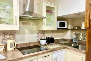 A kitchen with a microwave, toaster, kettle, and a glass cabinet. - AR-Rahman, 1 bed + 1 Living room apartment (Dartford)