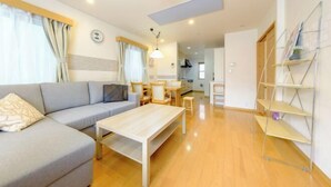 Ein modernes Wohnzimmer mit Sofa, Couchtisch und einer Essecke mit Stühlen.