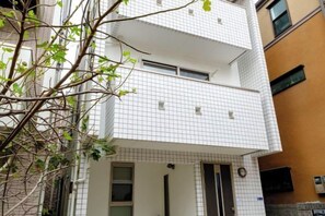 A multi-story residential building with a tiled facade, a balcony on the upper floor, and a door with a small window. - Beyond Comfort Shinjuku Okubo (Tokyo)