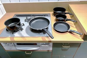 A kitchen with a stove, four frying pans, and a dishwasher. - GUEST HOUSE X (Tokyo)