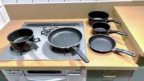 A kitchen with a gas stove, four frying pans, and a dishwasher. - GUEST HOUSE X (Tokyo)