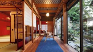 Een traditionele Japanse kamer met tatami vloeren, schuifdeuren en uitzicht op een tuin.