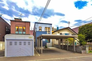 A residential property with a garage, a covered outdoor area, and a brick building. - THE SMILE (Sapporo)