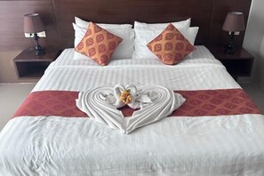A neatly made bed with white and red linens, two patterned pillows, and a heart-shaped floral arrangement on the bedspread. - KT8 Hotel Aonang (Krabi)
