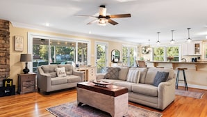A spacious living room with a high ceiling fan, a fireplace, and a view of the outdoors.